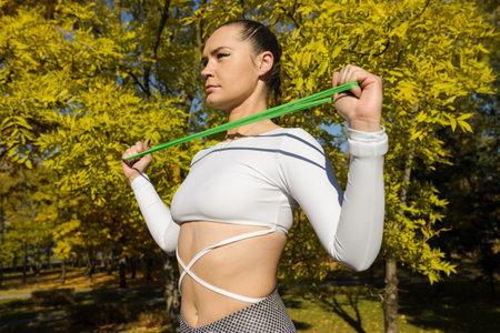 A fitness trainer warms up with a fitness elastic band in a city park.
