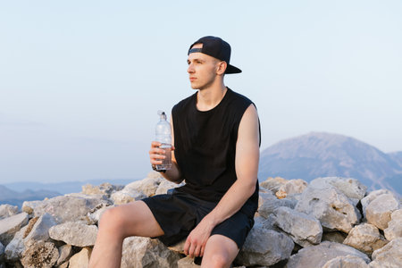 Portrait of a man drinking water against the background of mountains. vacation in the mountains