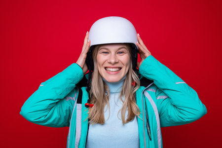 Portrait of a young woman in a ski helmet on a red background. Skiing and snowboardingの写真素材