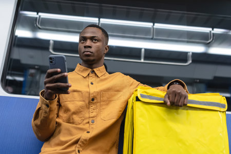 Portrait of a courier with a mobile phone who goes to the subway. Delivery from restaurantsの写真素材