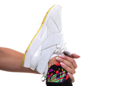 Close-up of a young woman holding a sneaker. Stretching before trainingの写真素材
