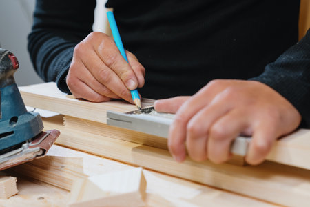 Close-up of the carpenter's hands marking the board with a pencil before starting work. Manufacture...