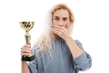A young woman holds a gold cup in her hand and the second one closes her mouth. The concept of...