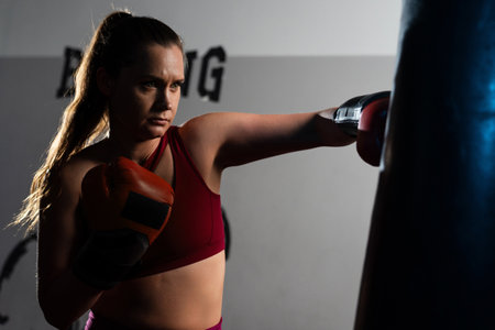 Athletic woman hits a punching bag with gloves