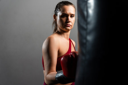 A boxer woman hits a punching bag on a dark backgroundの写真素材