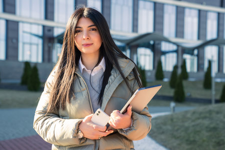 Portrait of a young woman with laptops on the background of an office buildingの写真素材