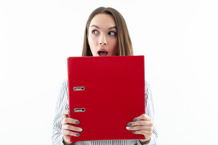 The organizer professional - a young woman office employee keeps all her important documents in a red folder, ready to access them at a moment's noticeの写真素材