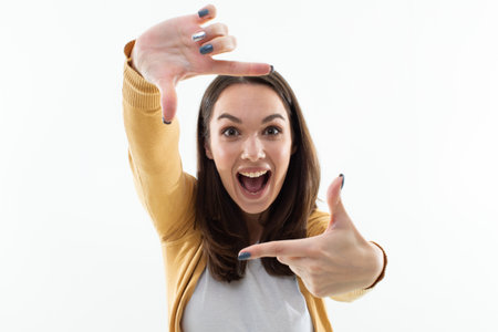 A beautiful brunette pretends to take pictures with her fingers. positive emotionの写真素材
