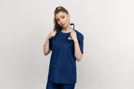 A young doctor in a blue suit is holding a stethoscope on a light background. Nurse on a white backgroundの写真素材