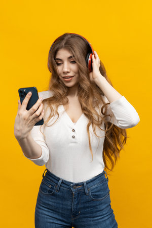 The joy of listening to music. Bright yellow background. A woman with headphonesの写真素材