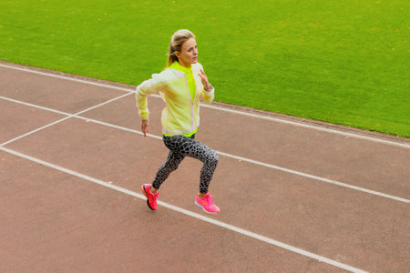 outdoor training. A young woman runs around the stadium. healthy lifestyleの写真素材