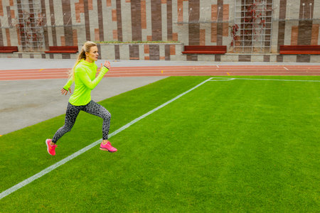 A female athlete during a workout outside. A young woman trains her running technique in an outdoor...