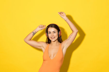 A happy young woman listens to music on a yellow background. summer vacation, swimwear advertisingの写真素材