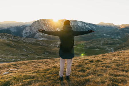 A woman enjoys a mountain view at sunsetの写真素材