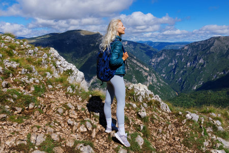 A young woman admires the mountain views after hiking in the summerの写真素材