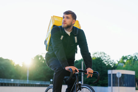 Portrait of a bearded male courier on a bicycle outside. Pizza delivery in the city in a fast way