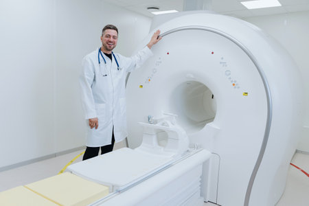 A smiling male doctor stands next to a professional MRI. Diagnostic room in the clinic.の写真素材
