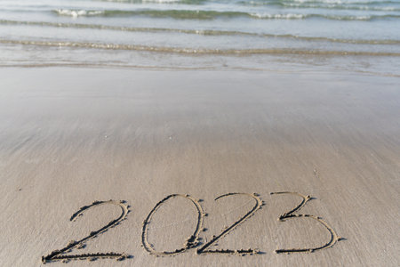 The year 2023 is written in the sand on the beach