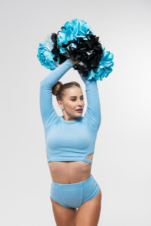 Cheerleading. Portrait of a young woman with bright makeup and hairstyle with pompoms on a white backgroundの写真素材