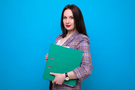 Portrait of a business woman with a green folders on a blue backgroundの写真素材