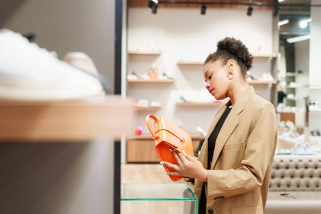 An African-American woman while choosing a fashionable handbag in a storeの写真素材