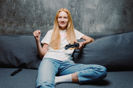 A young woman celebrates her victory in a video game. Online games from home during the pandemicの写真素材