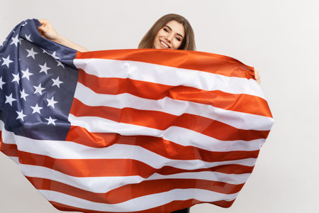 An American flag flying in the hands of a woman on a white background. The concept of love for the USAの写真素材