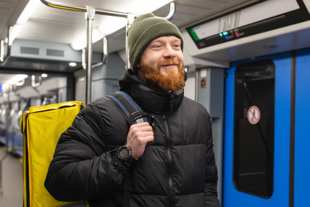 Portrait of a smiling courier man with a backpack in a subway carの写真素材