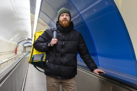 A successful pizza delivery man rides an escalator. Delivery in the city, professional food delivery from restaurantsの写真素材