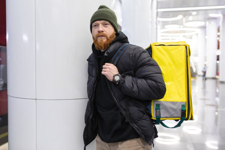 Portrait of a red-bearded man courier who is waiting for the subway on the platformの写真素材