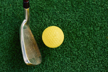 Close-up of a golf club and a yellow ball on the grass. Training courses. professional sports.の写真素材