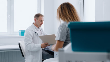 Patient's appointment with a doctor. A male doctor in a white coat reads a patient's medical record.の写真素材