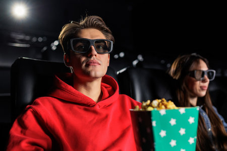 Portrait of a man in 3D glasses eating popcorn and watching a movie. Watching movies in the cinema