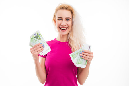 A happy young woman holds euro banknotes in her hands on a white background. The emotional portrait is isolated.の写真素材