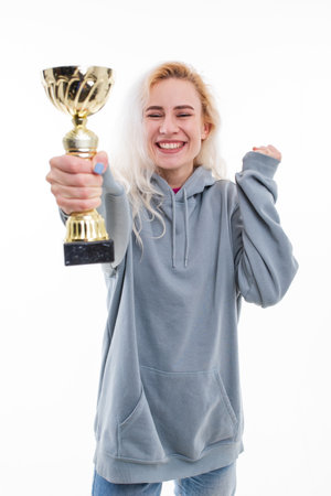 Emotions of a female athlete after winning a competition. The model holds the gold cup of the competition in her hands.の写真素材