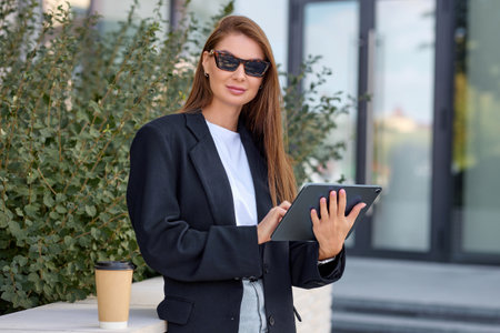 Young Caucasian woman with sunglasses works as a freelancer and checks social networks through a tablet.の写真素材