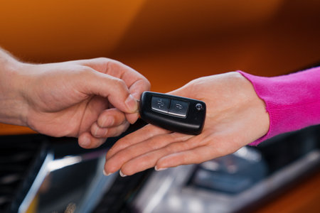Close-up of the car key that the manager hands over to the young woman to the buyer