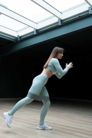 A young woman squats during a workout at home.の写真素材