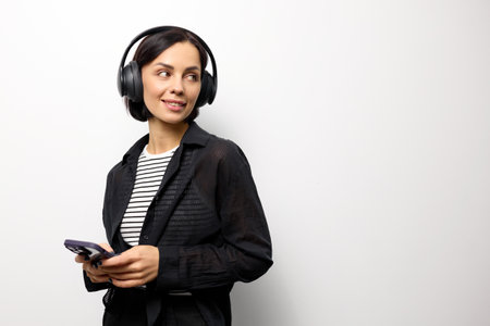 Portrait of a brunette woman with headphones and smartphone.の写真素材