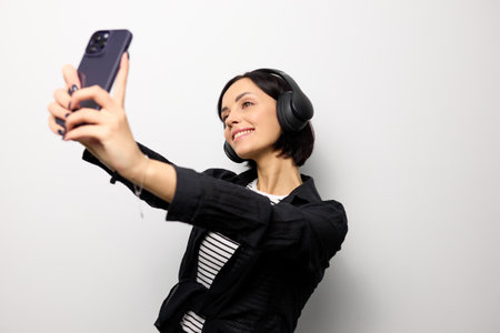 Portrait of a brunette woman with headphones taking a selfie.の写真素材