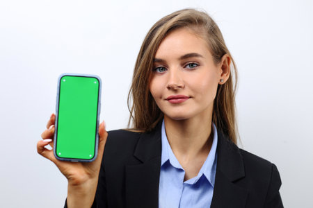 Young successful business lady holding smartphone vertically with green screen.の写真素材