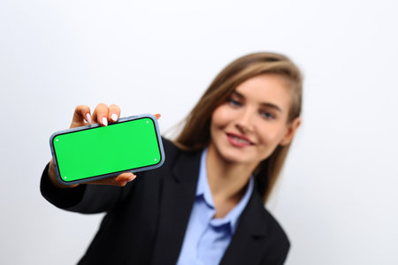 Cute female secretary showing smartphone green screen.の写真素材