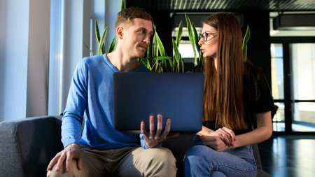 A man shows a female colleague business information on a laptop.