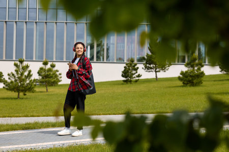 Laptop-wielding African-American woman walks purposefully from park to the office.