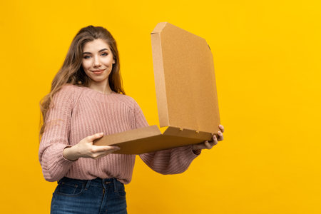 Spirit of a fast-paced food delivery service, with a woman holding pizza boxes on a bright yellow backgroundの写真素材