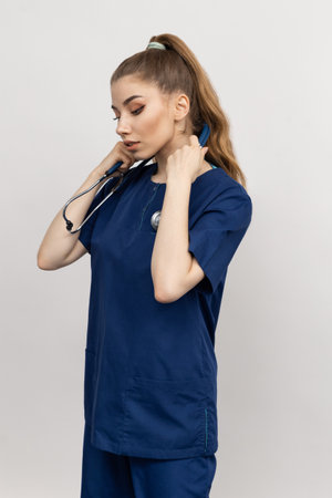 A nurse adjusts a stethoscope on a white background. A tired doctor after a work shiftの写真素材