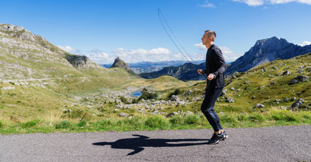 Panoramic photo of a man training on the background of a mountain landscape.