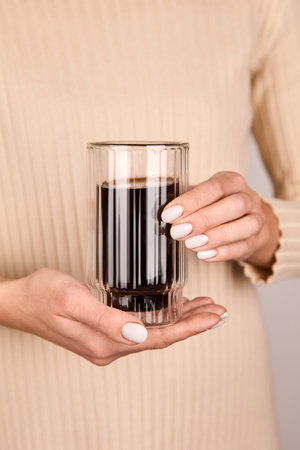 Woman holding glasses of coffee in her hands.