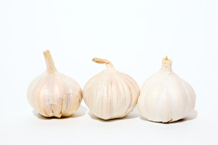 Three garlic cloves are placed in close proximity to each other, showing the distinctive papery skin and bulbous shape. The cloves appear fresh and ready for culinary use.の写真素材