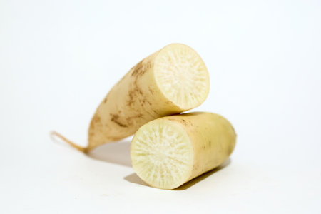 A freshly cut parsnip is placed against a stark white background, with one half standing upright and...